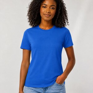 Op de afbeelding: Een effen koningsblauw T-shirt met korte mouwen en een ronde halslijn. Het kledingstuk heeft een standaard pasvorm, een rechte zoom en een gladde textuur. Het T-shirt wordt gecombineerd met een lichtblauwe spijkerbroek voor een casual look.