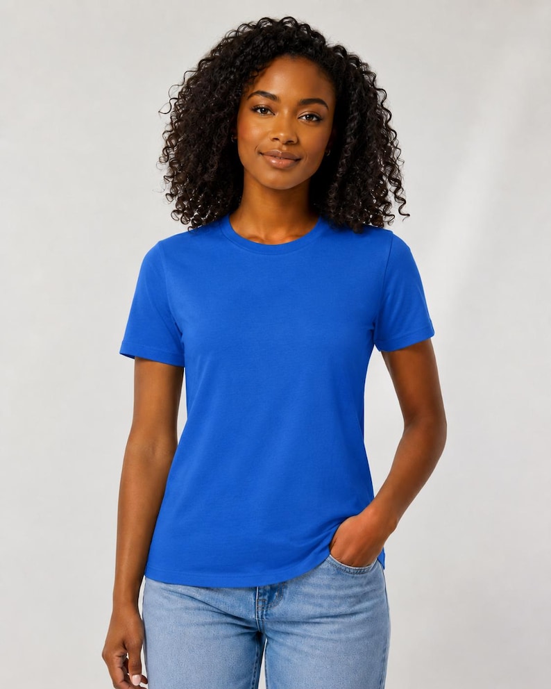 Op de afbeelding: Een effen koningsblauw T-shirt met korte mouwen en een ronde halslijn. Het kledingstuk heeft een standaard pasvorm, een rechte zoom en een gladde textuur. Het T-shirt wordt gecombineerd met een lichtblauwe spijkerbroek voor een casual look.