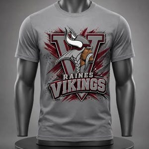May include: A grey short-sleeve t-shirt featuring a graphic of a Viking warrior in a horned helmet centered over a large letter V. The text RAINES VIKINGS is printed in bold, dark red and white lettering below the Viking illustration.