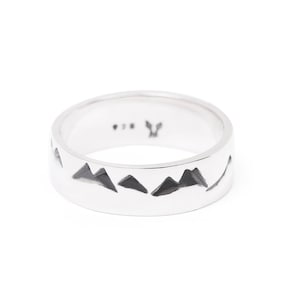 Puede incluir: Un anillo de plata con un dise&ntilde;o de cordillera grabado alrededor de la banda. El anillo est&aacute; marcado con una peque&ntilde;a "Y" en el interior.