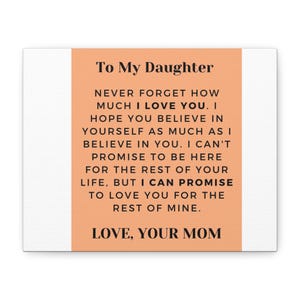 May include: A rectangular wall art piece with a peach-colored center panel and white borders. The text reads: To My Daughter, NEVER FORGET HOW MUCH I LOVE YOU. I HOPE YOU BELIEVE IN YOURSELF AS MUCH AS I BELIEVE IN YOU. LOVE, YOUR MOM.