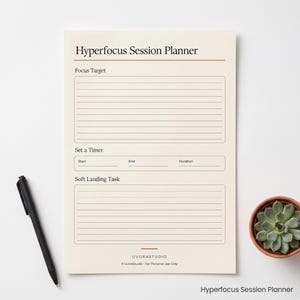 May include: A cream-colored Hyperfocus Session Planner sheet featuring sections for Focus Target, Set a Timer with fields for Start, End, and Duration, and Soft Landing Task. The page includes a black pen and a small potted succulent plant.