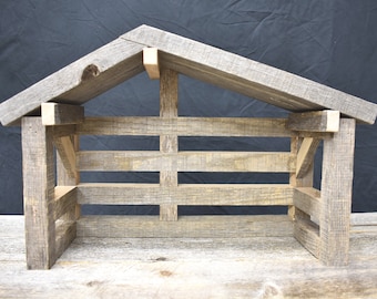 Peut inclure: Une étable de crèche en bois rustique avec un toit en pente. La structure est faite de bois gris vieilli, avec des panneaux avant et latéraux à lattes. Le design évoque la simplicité et l'artisanat traditionnel.