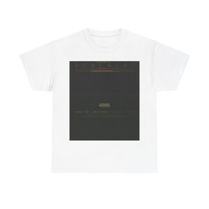 May include: A white short-sleeve t-shirt featuring a large, centered rectangular graphic on the chest. The graphic is a dark gray block containing small, mostly illegible text, with the yellow text 'one roulette' and 'the moving invisible' printed below.