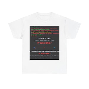 Peut inclure: Un t-shirt blanc à manches courtes avec un graphique rectangulaire noir sur la poitrine. Le graphique affiche des lignes de commande de terminal, des messages d'erreur et le texte : IT'S NOT DNS. THERE'S NO WAY IT'S DNS. IT WAS DNS.