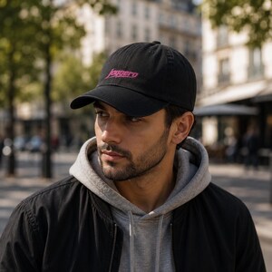 Peut inclure: Une casquette de baseball noire avec le mot Joggero brodé en fil rose sur le panneau avant. La casquette présente une visière incurvée, une calotte structurée avec un bouton sur le dessus et des œillets cousus pour la ventilation.