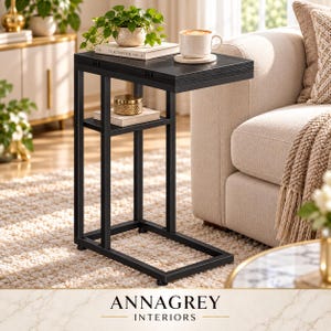 Peut inclure: Une table d'appoint en forme de C avec un plateau en bois noir et une structure en métal noir. La table comprend un plateau rectangulaire et une étagère inférieure. Le dessus supporte une tasse en céramique blanche, un livre et une plante.