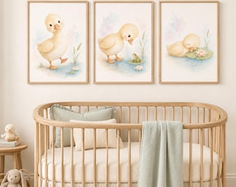 May include: Three framed watercolor prints featuring yellow ducklings in a pond setting. The left print shows a standing duckling, the center shows a duckling looking at a green frog, and the right shows a duckling resting on a lily pad.
