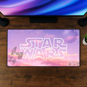 Può includere: Un tappetino da scrivania rettangolare con il logo bianco di Star Wars centrato su un cielo al tramonto rosa e viola. Il design include sagome di caccia TIE, il Millennium Falcon e la Morte Nera sullo sfondo di nuvole dai colori vivaci.