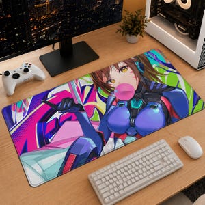 May include: A rectangular desk mat featuring a vibrant anime-style illustration of a character in a blue and black suit blowing a pink bubble. The background displays colorful graffiti-inspired patterns in shades of neon pink, green, and purple.