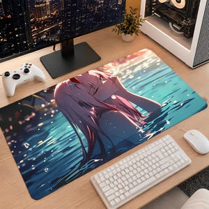 May include: A rectangular desk mat featuring an anime-style illustration of a character with long pink hair and a red horn, partially submerged in shimmering blue water. The artwork displays a serene expression with closed eyes and soft lighting.