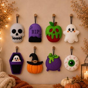 May include: A set of eight felt Halloween ornaments hanging on hooks. The designs include a white skull, a purple tombstone with RIP text, a red and green poison apple, a white ghost, a ghost in a purple coffin, a pumpkin with a witch hat, a purple cauldron with green liquid, and a white eyeball.