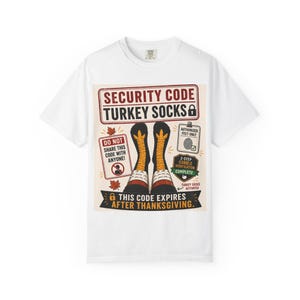 May include: A white t-shirt featuring a graphic design with the text SECURITY CODE TURKEY SOCKS, DO NOT SHARE THIS CODE WITH ANYONE, AUTHORIZED FEET ONLY, 2-STEP GOBBLE VERIFICATION COMPLETE, TURKEY SOCKS ACTIVATED, and THIS CODE EXPIRES AFTER THANKSGIVING.