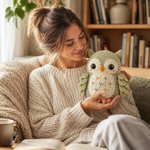 May include: A sage green and cream crocheted owl plush toy with large dark eyes, a small yellow beak, and embroidered star accents on its belly. The owl features textured wings and small orange feet, crafted with detailed yarn stitching throughout.