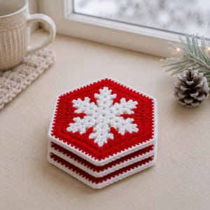 May include: A stack of three hexagonal crochet coasters featuring a white snowflake pattern centered on a vibrant red background. Each coaster is finished with a clean white border, creating a geometric design that highlights the intricate yarn work.