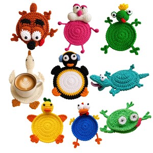 May include: A collection of nine colorful crochet coasters shaped like various animals and creatures, including a brown bear, pink character, green frog, white goose holding a coffee mug, black penguin, teal lizard, yellow duck, blue bird, and green frog.