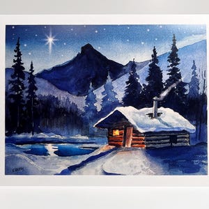 May include: Watercolor painting of a snow-covered cabin with a lit window, nestled in a winter landscape. The scene includes a mountain range, evergreen trees, and a starry night sky. A bright star shines above the cabin.