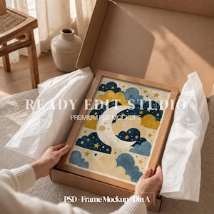 May include: A wooden frame containing a print of a smiling crescent moon surrounded by dark blue and yellow clouds and stars, nestled inside a cardboard shipping box with white tissue paper. The text READY EDIT STUDIO PREMIUM PSD MOCKUPS is visible.