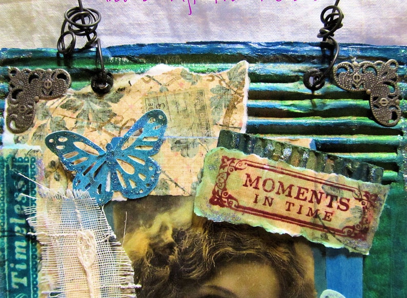 Pode incluir: Obra de arte em t&eacute;cnica mista com uma borboleta azul-turquesa, papel vintage e as palavras &laquo;Moments in Time&raquo;. A obra apresenta uma colagem de texturas, incluindo cart&atilde;o canelado e detalhes met&aacute;licos, com uma paleta de cores azul-turquesa, verde e s&eacute;pia.