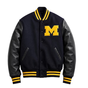 May include: A navy blue varsity jacket featuring black leather sleeves, a yellow letter M patch on the chest, and yellow striped ribbed trim on the collar, cuffs, and hem. The jacket includes a snap button front closure and two side pockets.