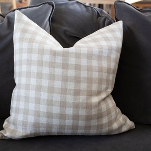 May include: A beige and white gingham throw pillow on a dark gray couch.