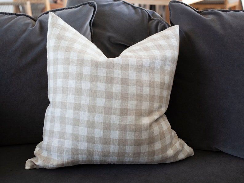 May include: A beige and white gingham throw pillow on a dark gray couch.