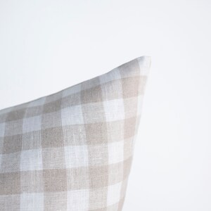 May include: A beige and white gingham pillow cover. The pillow cover is made of a soft, textured fabric.