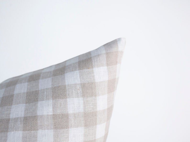 May include: A beige and white gingham pillow cover. The pillow cover is made of a soft, textured fabric.