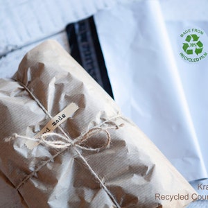 May include: A brown paper package tied with twine and labeled "hand made". The package is being shipped in a white recycled courier envelope with a green label that says "Made from 70% Recycled Film".