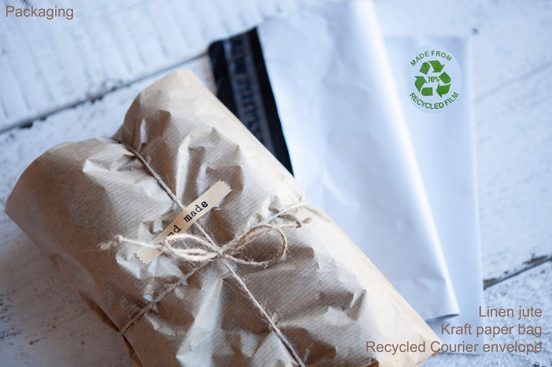 May include: A brown paper package tied with twine and labeled "hand made". The package is being shipped in a white recycled courier envelope with a green label that says "Made from 70% Recycled Film".