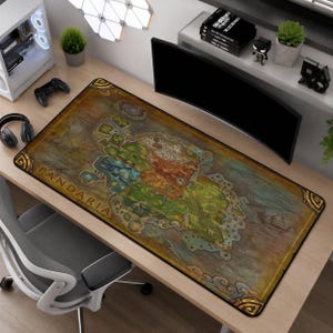 May include: A rectangular desk mat featuring a detailed, colorful map of the continent of Pandaria. The design includes varied terrain, islands, and the text PANDARIA in a stylized font, bordered by a decorative gold frame on a dark background.