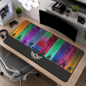 May include: A rectangular desk mat featuring a vibrant, multi-colored vertical striped background in shades of orange, green, purple, red, and blue. The mat displays black silhouettes of various characters and a white Triforce emblem at the bottom.