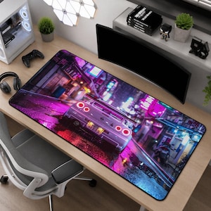 Pode incluir: Um tapete de secretária retangular com uma ilustração digital vibrante de um carro desportivo prateado visto de trás, num cenário de rua urbana iluminada por néones à noite com reflexos roxos e azuis intensos no pavimento molhado.