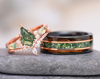 Könnte beinhalten: Ein Verlobungsring aus Roségold mit einem drachenförmigen Moosachat-Mittelstein, kleinen Akzentsteinen und einem passenden Ring sowie ein schwarzer Ring mit einer Mitteleinlage aus Moosachat und roségoldenen Streifen.