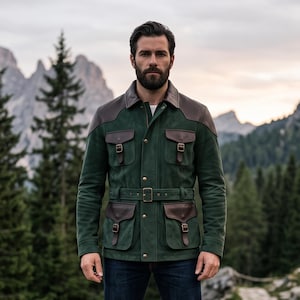 May include: A dark green suede field jacket featuring brown leather shoulder patches, a matching brown leather collar, and four front pockets with buckled straps. The jacket includes a central button closure and a matching green suede waist belt.