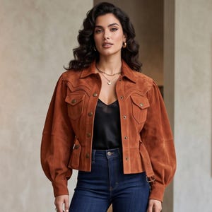 May include: A rust-colored suede jacket featuring a pointed collar, long puff sleeves with buttoned cuffs, and two chest pockets with flaps. The jacket has a front button closure, a belted waist with a buckle, and decorative western-style stitching.