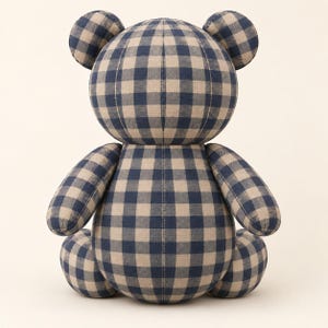 Puede incluir: Un oso de peluche relleno con un patr&oacute;n cl&aacute;sico de cuadros vichy en azul marino y beige. La figura de felpa tiene una cabeza redonda con dos orejas peque&ntilde;as, un cuerpo esf&eacute;rico grande, dos brazos extendidos y dos piernas en posici&oacute;n sentada.