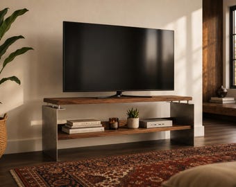 Op de afbeelding: Een televisiemeubel met een bovenblad en een onderste plank van donker hout, ondersteund door twee zijpanelen van geborsteld metaal. Het meubel draagt een flatscreen-televisie, terwijl de onderste plank twee gestapelde boeken, een kaars, een kleine potplant en een zilverkleurig elektronisch apparaat bevat.