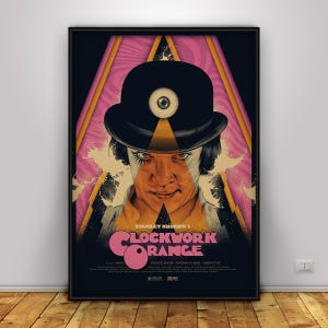 Pode incluir: Um cartaz de filme emoldurado de A Clockwork Orange de Stanley Kubrick com uma ilustração central de uma pessoa usando um chapéu-coco preto com um símbolo de olho na copa, sobre um fundo geométrico rosa e preto com texto.