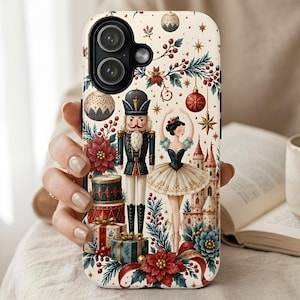 May include: A cream-colored phone case featuring a festive holiday pattern with a nutcracker, a ballerina, a castle, wrapped gifts, red poinsettias, pine branches, and hanging ornaments. The design includes gold star accents and berries.