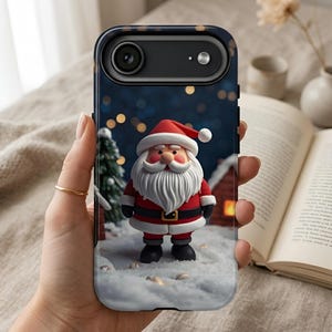 May include: A dark blue smartphone case featuring a 3D-style illustration of Santa Claus standing in snow. Santa wears a red suit with white trim, a matching hat, and black boots. A small green pine tree and a house are visible in the background.