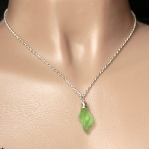 May include: A silver chain necklace with a light green glass pendant shaped like a teardrop.