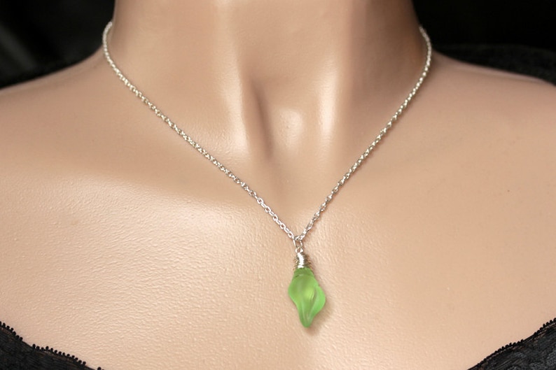 May include: A silver chain necklace with a light green glass pendant shaped like a teardrop.