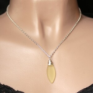 May include: A silver chain necklace with a light yellow teardrop-shaped pendant.