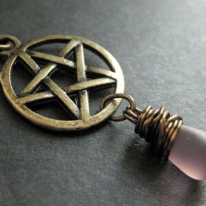May include: A silver pendant necklace with a pentagram charm and a purple glass teardrop pendant.