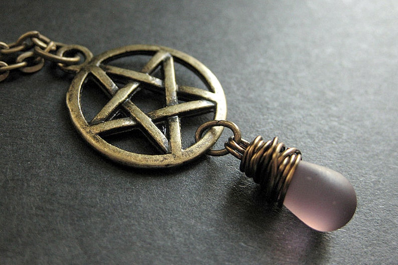 May include: A silver pendant necklace with a pentagram charm and a purple glass teardrop pendant.
