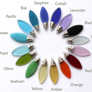 May include: A selection of 16 glass pendants in various colors, including teal, sapphire, cobalt, lavender, black, white, pink, red, orange, yellow, amber, seafoam, olive, aqua, ocean, and pacific. Each pendant is shaped like a teardrop and has a silver wire wrapped around the top.