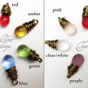 May include: Two rows of glass teardrop charms, each wrapped in wire. The top row features clear glass charms in colors like pink, red, amber, and clear. The bottom row features satin glass charms in colors like green, blue, purple, and clear/white.