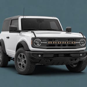 May include: A white two-door SUV with a black grille, black wheel arches, and black bumpers. The front grille features the word BRONCO in bold lettering. The vehicle has round headlights, a black roof, and dark gray wheels with all-terrain tires.