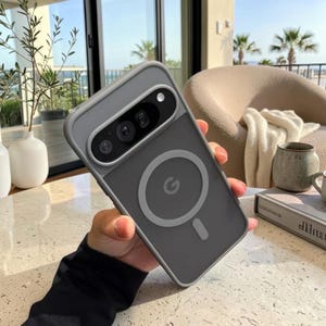 May include: A matte gray smartphone case designed for a Google Pixel device, featuring a prominent circular magnetic charging ring on the back, a vertical alignment strip, and a raised cutout section to accommodate the rear camera array.
